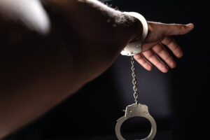 Criminal hand with handcuffs on black background. The scene is situated in controlled studio environment in front of black background. Photo is taken with SONY AIII camera.